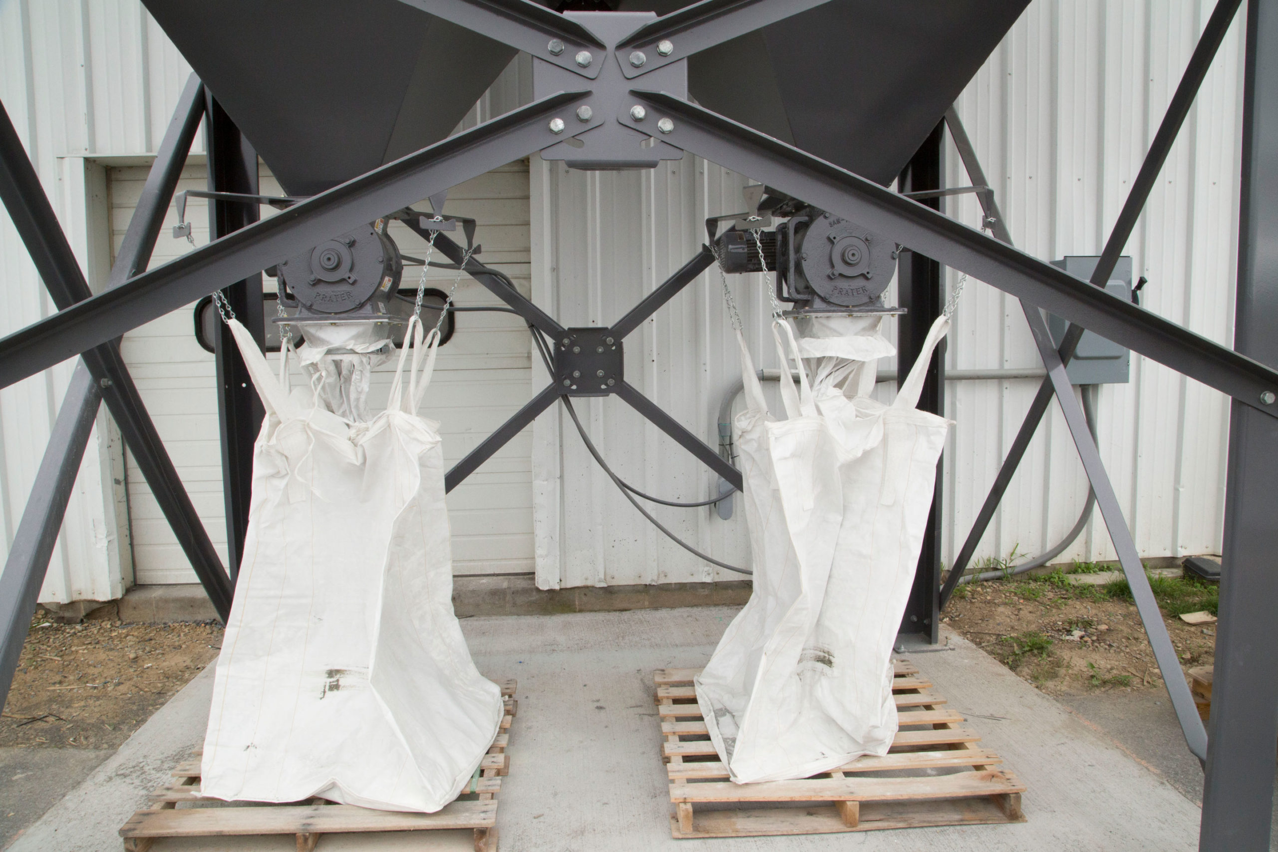 two cast rotary airlocks mounted on hopper with dust bags hanging underneath