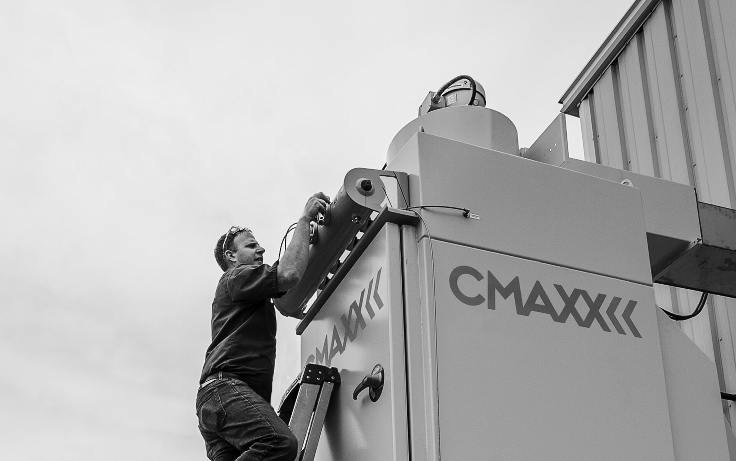 Serviceman inspecting compressed air header valves on a CMAXX dust and fume collector installation